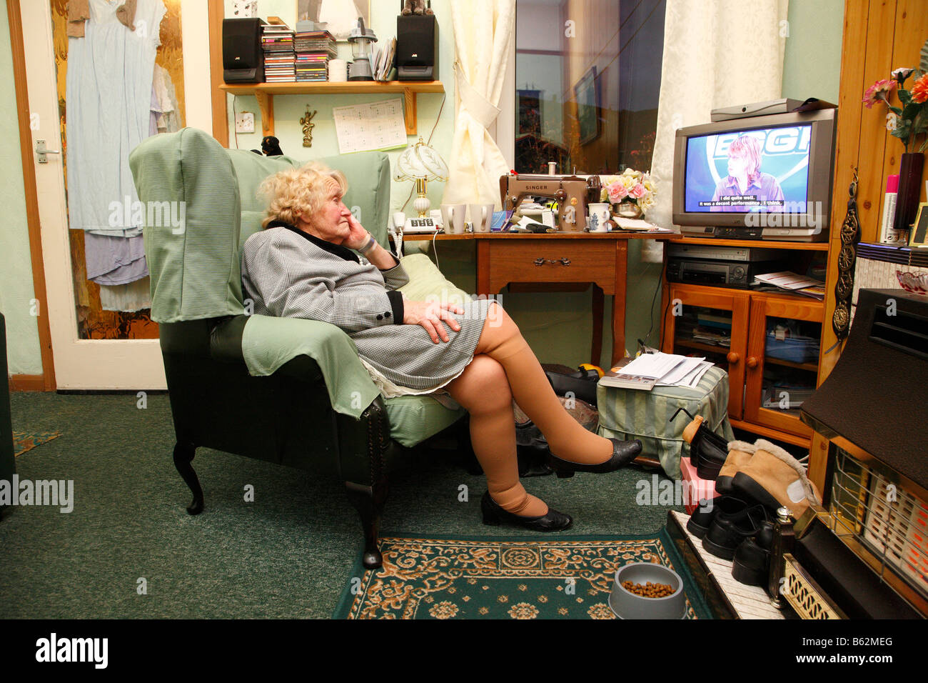 old-woman-sitting-in-a-chair-watching-tv-B62MEG.jpg