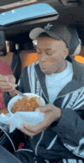 a man is sitting in a car eating a bowl of food