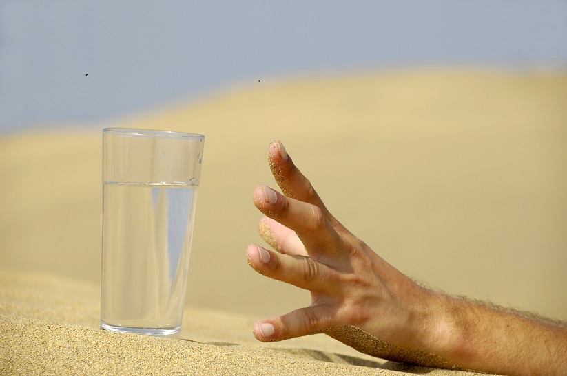 hand-reaching-for-a-glass-of-water-in-the-desert.jpg