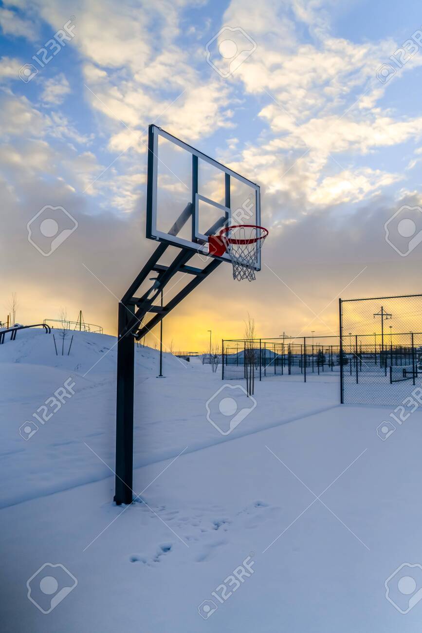 Snow covered outdoor basketball court at sunset - 116283781