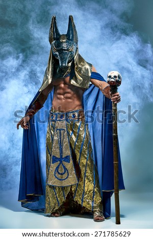 stock-photo-the-man-in-the-image-of-the-ancient-egyptian-pharaoh-with-a-mask-of-anubis-on-his-face-on-blue-271785629.jpg
